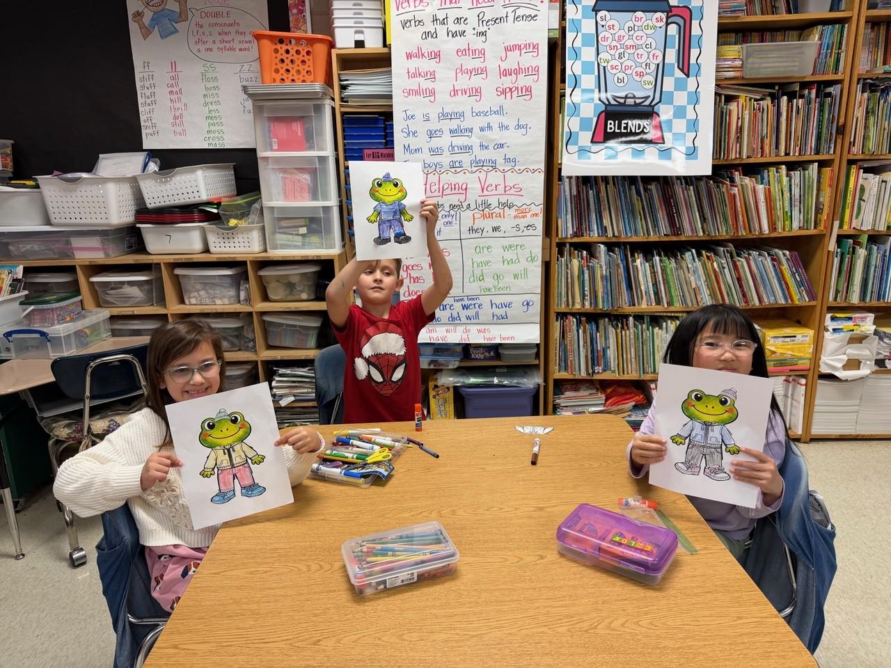 Students practicing names of colors and clothing by coloring articles of clothing and pasting it on the frog named Felix, the mascot for these German lessons.